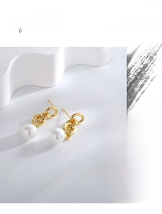 Close-up of elegant gold-plated triple chain drop earrings with white shell pearls