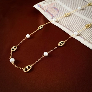 Detail of gold-plated necklace featuring white pearls and elegant coffee bean links