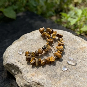 Macro shot of tiger eye stone moon hair clip on a natural rock with garden background
