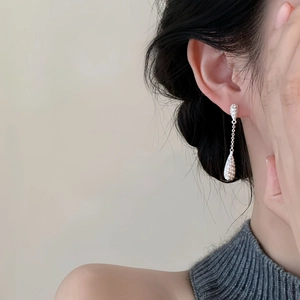 Close-up of a silver long teardrop earring with cubic zirconia worn by a model