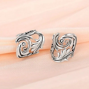 Detail of vintage silver leaf ear cuff with hollow floral patterns and oxidized finish
