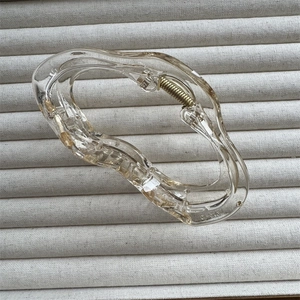 Detailed close-up of transparent cloud-shaped hair claw with gold spring mechanism