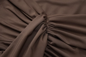 Detailed close-up of brown pleated fabric with twist knot design and knit texture