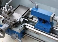 Macro view of industrial iron metal lathe machine components including tool post and tailstock