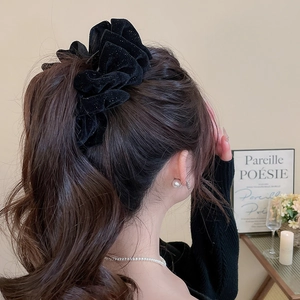 Gros plan d'un grand chouchou en velours noir pailleté sur des cheveux bruns ondulés