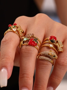 Detailed view of stacked enamel ladybug, strawberry, and leopard motif rings on fingers
