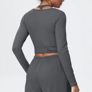 Detail of cross-strapped back on dark gray long sleeve cropped top and high waist yoga pants