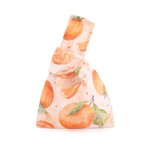 Detail of velvet wrist bag with orange fruit print and watercolor floral pattern
