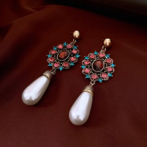 Detail of vintage gold earrings with red gems and white teardrop pearls on silk