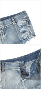 Dettaglio dei bordi sfrangiati e della cerniera metallica sui pantaloncini di jeans chiari