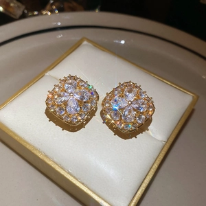 Detail of gold-plated square clover earrings with cubic zirconia in a jewelry box