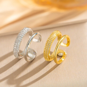 Close-up of gold and silver double-layered open rings with zircon stones on silk cloth