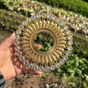 Detailed view of round gold metal wall decor with sparkling crystals and radial textures