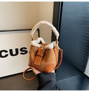 Detail of autumn bucket bag with brown suede finish and white faux shearling trim