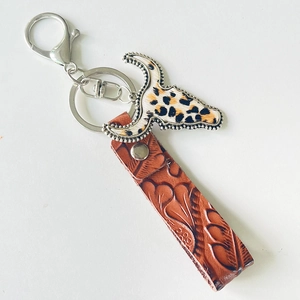 Vintage western leather keychain with leopard bull head pendant on white background