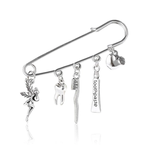 Silver alloy safety pin brooch with dental charms like fairy tooth and toothbrush