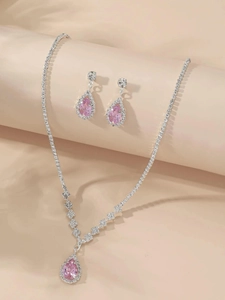 Close-up of bridal jewelry set with pink teardrop stones and silver zircon necklace