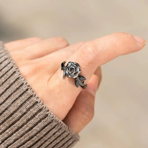 Primo piano di un anello a rosa nera vintage con dettagli di foglie indossato