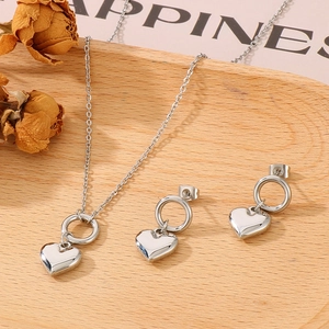 Polished silver heart necklace and stud earrings set on a rustic wooden tray decoration