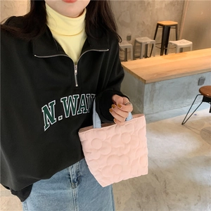 Pink quilted lunch bag with floral pattern held by a model in a cafe setting