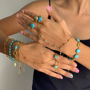 Bohemian gold hand chain set with turquoise beads and rings on a female model