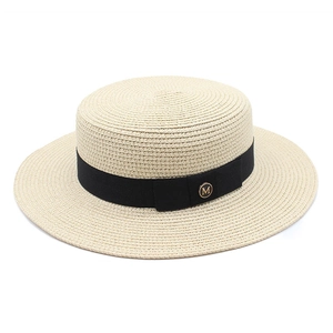 Détail d'un chapeau de paille avec ruban noir et boucle métallique dorée lettre M