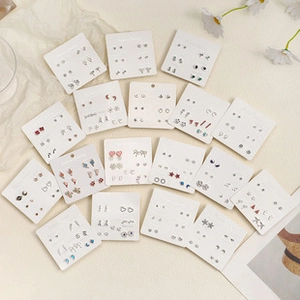 Detailed flat lay of Christmas earring sets featuring festive house and glove motifs