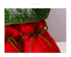 Detail of red felt Christmas gift bag with green knitted drawstring and bow decoration