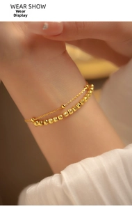 Detail of a double-layered golden bracelet with textured beads on a woman's wrist