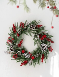 Close-up of Christmas wreath with pine needles, red berries, cones and snow details