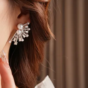 Elegant fan-shaped drop earrings with white pearls and sparkling crystals on model