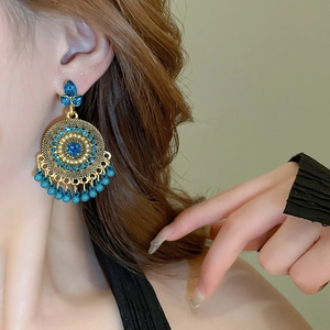Detail view of Bohemian tassel earrings with blue stones and turquoise beads on a model