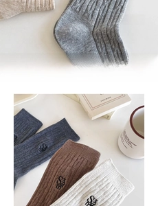 Détail de chaussettes en coton côtelé avec broderie de lettres aux tons terreux