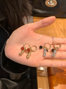 Détail de boucles d'oreilles pendentif cacahuète en or avec perles rouges et argent noir