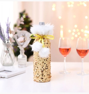 Detail of gold sequin wine bottle cover with white faux fur collar and pom-poms