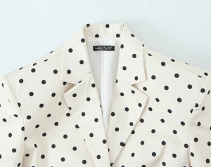 Détail d'un blazer beige à pois montrant la texture du tissu et l'étiquette de taille
