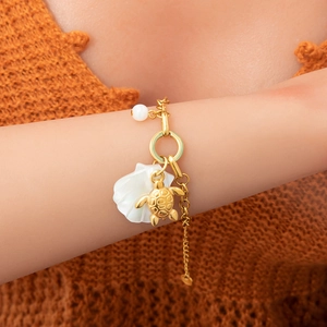 Détail du bracelet océan plaqué or 18 carats avec pendentifs tortue, coquillage et perle