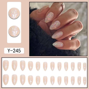 Faux ongles courts en amande champagne doré avec paillettes colorées et base rose nude