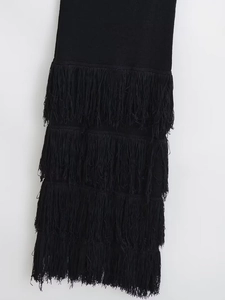 Vue détaillée des franges noires superposées et de la maille sur une robe longue ajustée