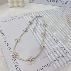 Beige beaded starfish necklace with silver extension chain on Kinfolk book