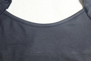 Detail of high-density black knit fabric showing double-needle neckline stitching and texture
