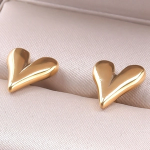 Close-up of heart-shaped gold 304 stainless steel earrings on a beige leather box