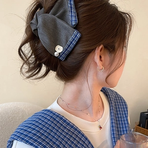 Detail of plaid bow hair claw clip with pearl and button accents on hair