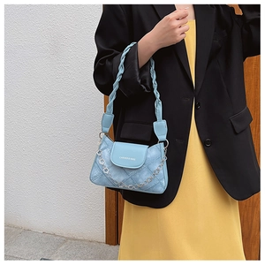 Detail of light blue denim texture bag with woven strap and floral metal chain