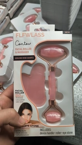 Detail of rose quartz facial roller and gua sha set in a retail window packaging box