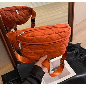 Detail of orange quilted nylon crossbody bag featuring silver zippers and adjustable strap