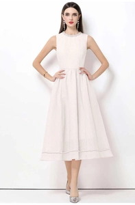 Détail de l'encolure perlée et du tissu texturé sur une robe midi blanche sans manches