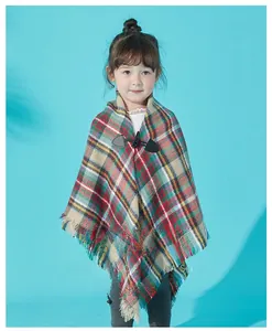 Detail of plaid kids' poncho featuring classic horn button and soft fringe edges