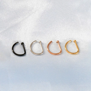 Macro view of D-shaped nose rings in black, silver, rose gold, and gold on blue silk