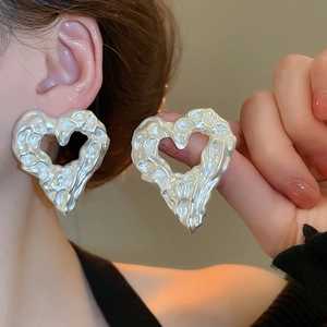 Detail of silver heart earrings with irregular lava texture and metallic molten design